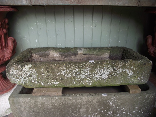 A weathered rough hewn natural stone trough of shallow rectangular form 110 cm long x 50 cm wide x