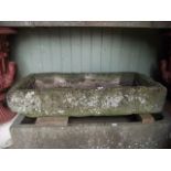 A weathered rough hewn natural stone trough of shallow rectangular form 110 cm long x 50 cm wide x