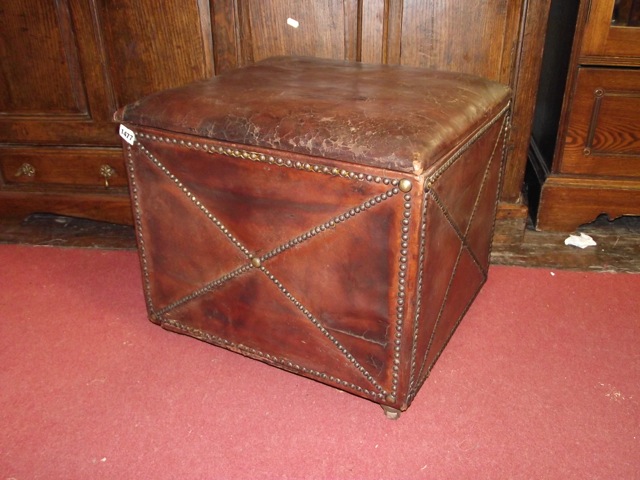 An old English style tan leather clad box stool with hinged lid and applied brass studwork detail