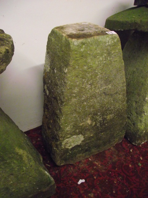 A weathered natural stone staddle stone base of square tapered form