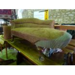 A Victorian upholstered day bed with raised and partial curved back, raised on turned supports and