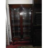 A 1920s slim oak freestanding bookcase enclosed by a pair of three quarter length leaded light