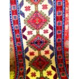 A wool runner with central cream field decorated with medallions in shades of red, blue and green,