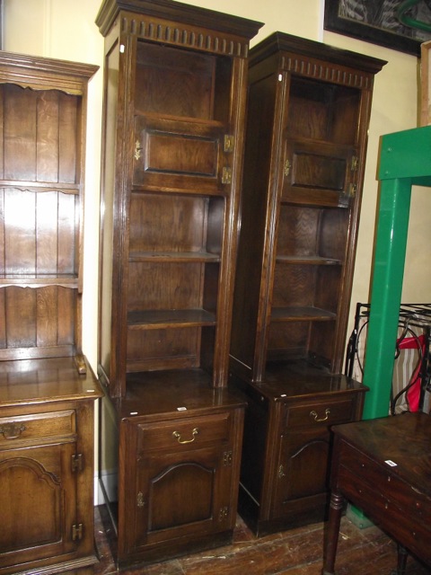 A matched pair of tall and slender oak side cupboards in the old English style, the upper sections