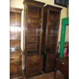 A matched pair of tall and slender oak side cupboards in the old English style, the upper sections