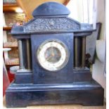 A Victorian black slate mantel clock in the classical style with brass column supports and