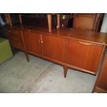 A mid-20th century low and long teak sideboard enclosed by three doors and three drawers with