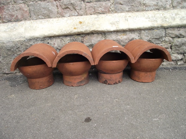 Four reclaimed terracotta chimney pot cowls with arched vents