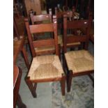 A set of four oak ladder back dining chairs with rush seats raised on square, cut and chamfered