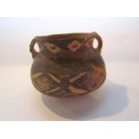 A two handled terracotta vessel with simple painted geometric decoration, probably Eastern in