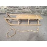 A vintage toboggan with beechwood frame, slatted seat and iron fittings stamped Davos