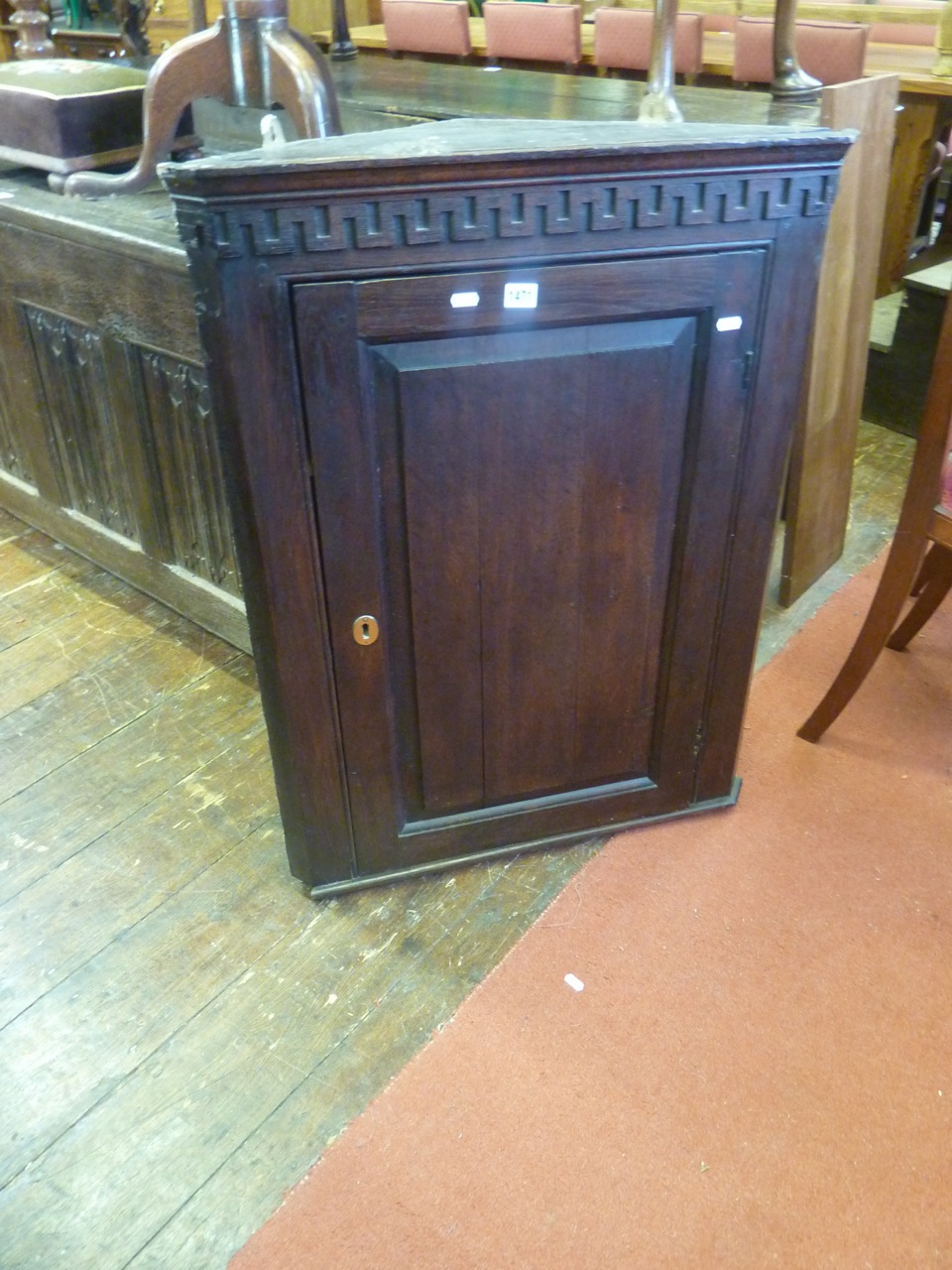 A Georgian oak hanging corner cupboard enclosed by a rectangular fielded panelled door beneath an