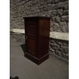 A late Victorian mahogany bedside cupboard enclosed by a panelled door with carved floral detail and