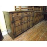 A good quality reproduction oak dresser base in the old English style enclosed by a pair of twin