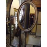 An Edwardian gilt frame wall mirror of oval form with bevelled edge plate and moulded surround,