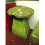 A natural stone staddle stone with square tapered base beneath a domed cap