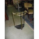 A brass umbrella stand of demi-lune form with tubular frame and cast iron base