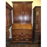 A Georgian oak bureau cabinet, the upper section enclosed by a pair of arched fielded panelled doors