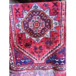 An eastern wool rug with central star shaped medallion detail upon a red field with concentric