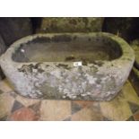 A small weathered natural stone trough of rectangular form with rounded ends, 68 cm long x 38 cm