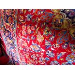 A substantial eastern wool carpet with deep red ground with trailing floral decoration and