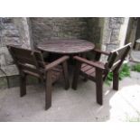 A weathered contemporary stained hardwood garden table of circular form with slatted top raised on