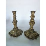 A pair of heavy cast brass candlesticks with lion mask and other scrolling detail raised on