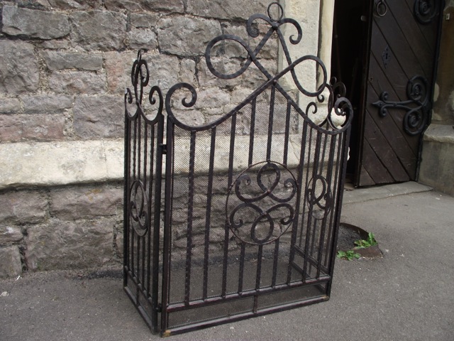 A three-fold ironwork fire/spark guard with entwined scrollwork detail