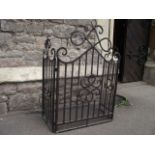 A three-fold ironwork fire/spark guard with entwined scrollwork detail