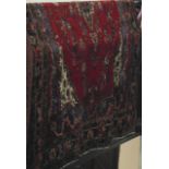 A substantial eastern wool carpet with deep red field set with a central medallion of foliate and