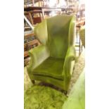 A Georgian style wing armchair with shaped outline, pale green dralon upholstery and loose squab