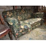 An Edwardian two seat sofa with rolled arms, upholstered in 'Golden Lily' patterned Sanderson