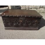 A small antique oak box with hinged lid, ironwork carrying handles and carved front elevation