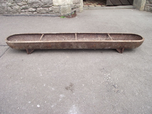 A small vintage cast iron feeding trough of slender rectangular form with rounded ends, 4ft long