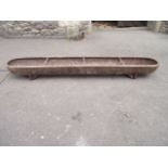 A small vintage cast iron feeding trough of slender rectangular form with rounded ends, 4ft long
