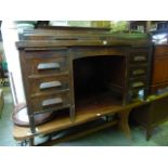 An early 20th century oak kneehole twin pedestal desk with shallow tambour roll top over a