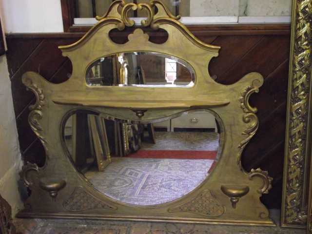 An Edwardian overmantel mirror with shaped outline, c-scroll and further detail, later gilded finish