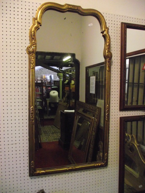 A Queen Anne style wall mirror with gilded and arched moulded frame with shell and further detail,