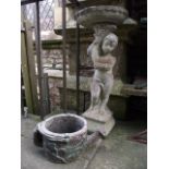 A contemporary cast composition stone bird bath in the form of a cherub supporting a cornucopia