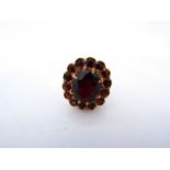 A gem-set ring, centred with an oval mixed-cut untested garnet weighing approximately 4.45cts,