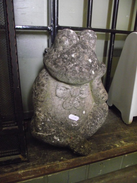 A small weathered cast composition stone garden ornament in the form of a seated contemplating frog