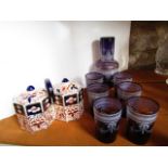 An amethyst glass carafe together with seven associated beakers, all with gilded rims and further