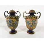 A pair of Doulton Lambeth two handled vases and covers with relief moulded floral and other detail