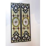A pair of leaded glass panels of rectangular form with symmetrical decoration in shades of blue, red