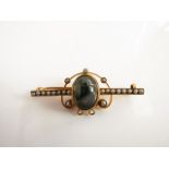 An Edwardian style bar brooch, centred with an oval cabochon moss agate which swivels to reveal