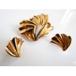 A 9ct gold set, comprising: a brooch and a pair of stud earrings, each of stylised leaf form, with