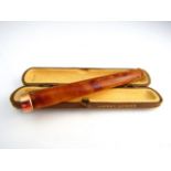 An amber and 9ct rose gold cigarette holder, Asprey & Co., contained in the original Asprey fitted