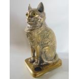 An unusual cast brass inkwell in the form of a seated cat, well modelled with inset yellow glass