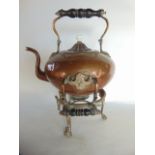 A heavy antique copper kettle raised on associated stand with turned ebonised timber handles, the