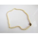 A strand of sixty-three pearls, measuring: 5.5mm x 6mm approx., with a 9ct gold flower head clasp,